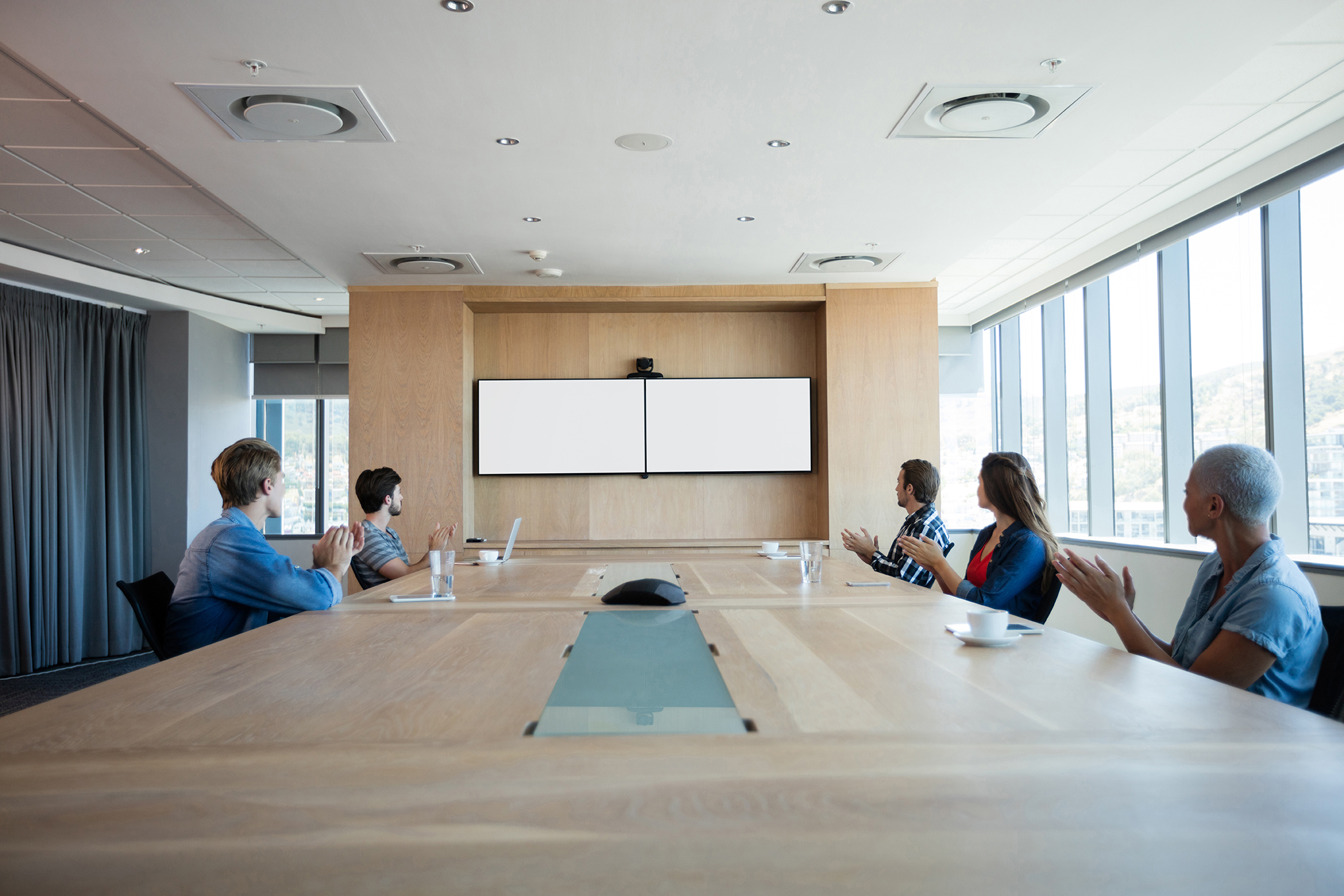 Creative business team applauding while attending a conference call in office